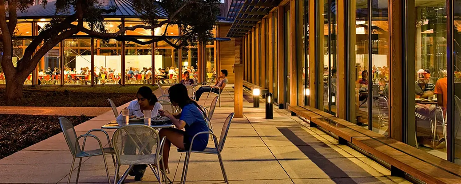 Students sitting outside at night in front of Duncan Commons